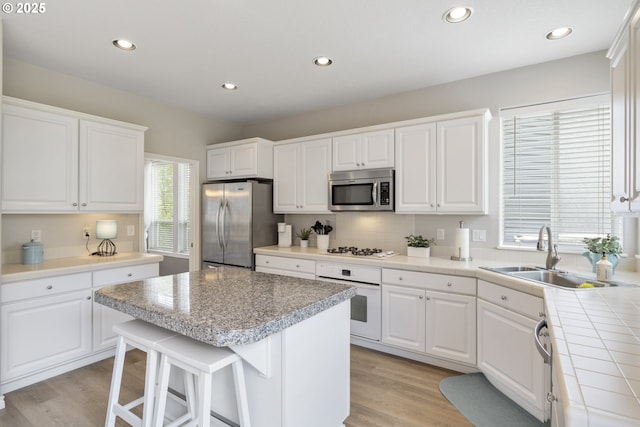 16205 SW Blackbird Dr, Beaverton, OR 97007 - kitchen featuring appliances with stainless steel finishes, a sink, white cabinetry, a kitchen island, and light wood finished floors