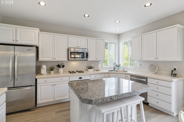 16205 SW Blackbird Dr, Beaverton, OR 97007 - kitchen featuring stainless steel appliances, a sink, light wood finished floors, recessed lighting, and white cabinets