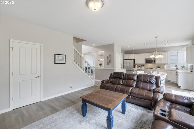 16205 SW Blackbird Dr, Beaverton, OR 97007 - living room with light wood-type flooring, stairs, a chandelier, and baseboards