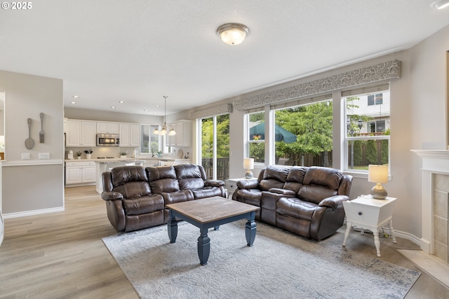 16205 SW Blackbird Dr, Beaverton, OR 97007 - living area with light wood-style floors, healthy amount of natural light, a chandelier, recessed lighting, and baseboards