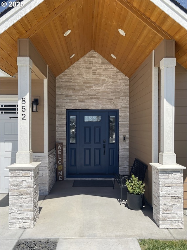 view of exterior entry featuring stone siding and covered porch