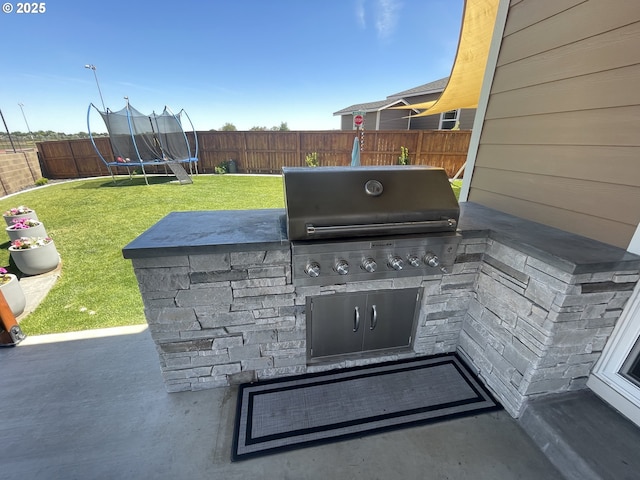 view of patio with area for grilling, a trampoline, and an outdoor kitchen