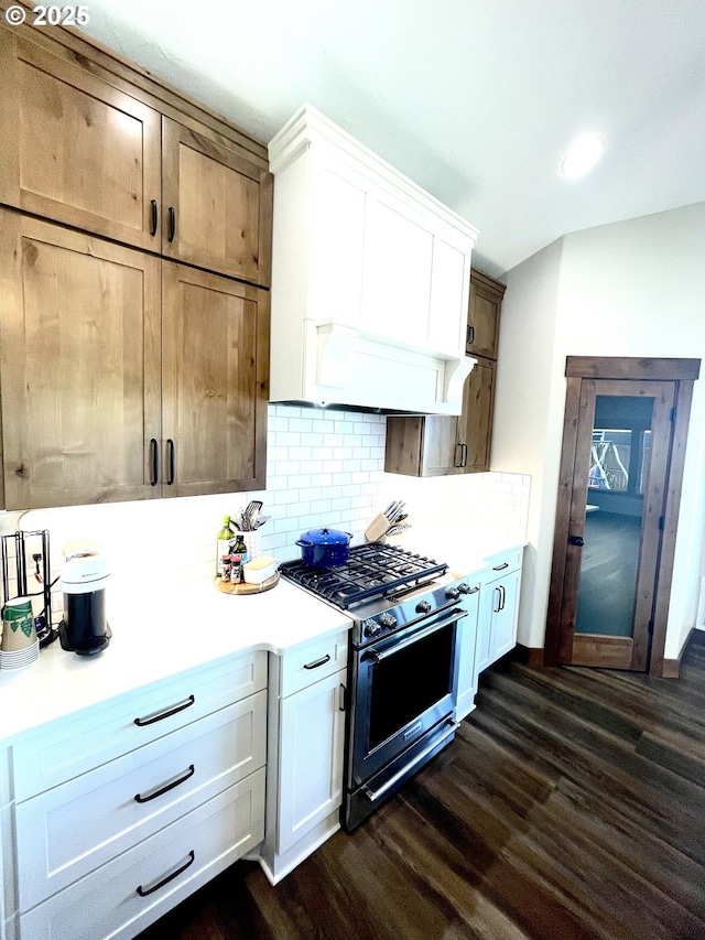 kitchen featuring gas stove, dark wood finished floors, tasteful backsplash, light countertops, and white cabinetry