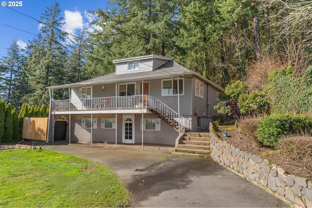 view of front of house with stairs, driveway, and a front lawn