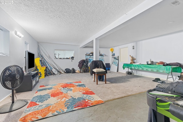 playroom with a textured ceiling, visible vents, and concrete flooring