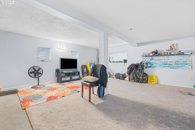 living area featuring visible vents, a textured ceiling, and baseboards