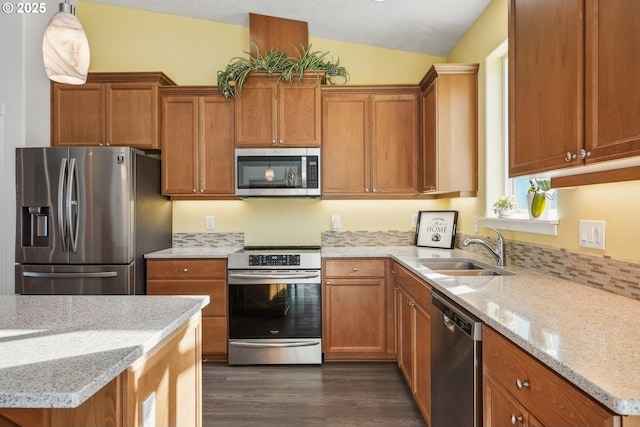 kitchen featuring pendant lighting, sink, dark hardwood / wood-style flooring, light stone counters, and stainless steel appliances