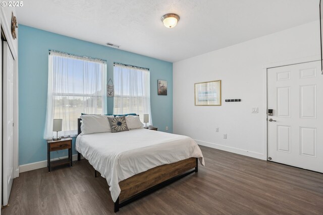 bedroom with baseboards, wood finished floors, and visible vents