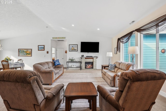 living room with a fireplace, vaulted ceiling, and light colored carpet