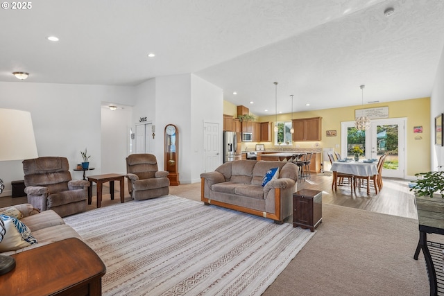 living room with lofted ceiling, french doors, and light wood-type flooring