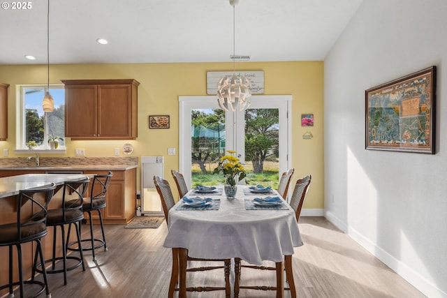 dining area with a chandelier, sink, and light wood-type flooring