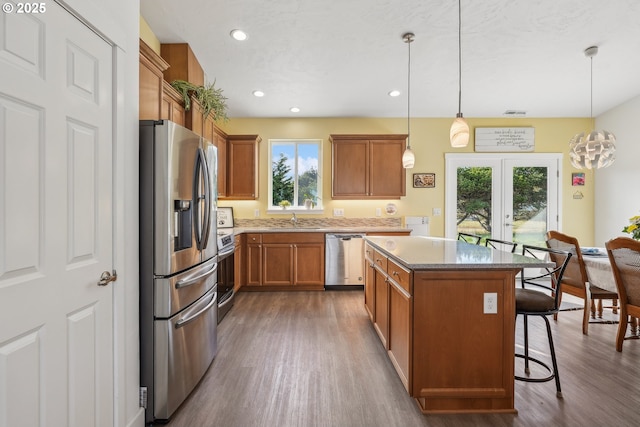 kitchen featuring a kitchen island, decorative light fixtures, sink, a kitchen breakfast bar, and stainless steel appliances