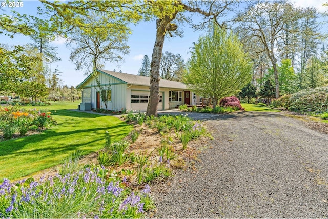 ranch-style house with board and batten siding, driveway, a front yard, and a garage