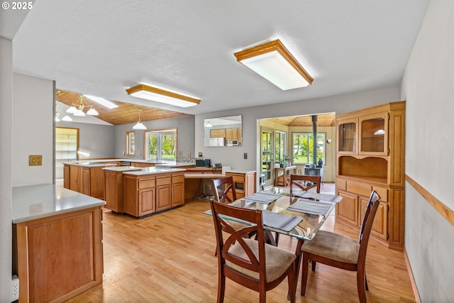 dining room featuring lofted ceiling, a healthy amount of sunlight, and light wood-style flooring