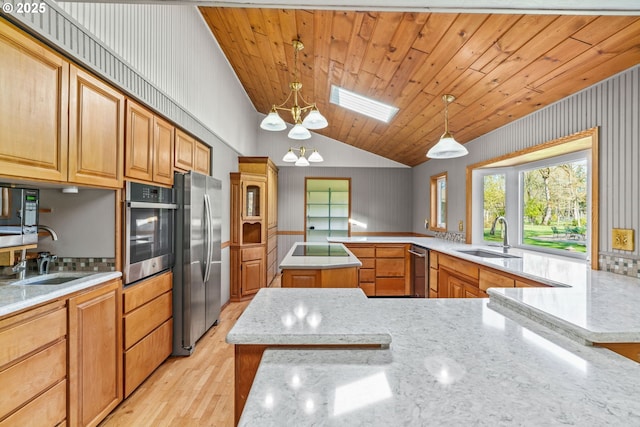 kitchen featuring lofted ceiling with skylight, light wood-type flooring, stainless steel appliances, and a sink