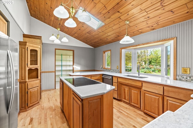 kitchen featuring vaulted ceiling with skylight, light wood-type flooring, freestanding refrigerator, and a sink