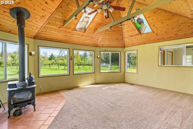 unfurnished sunroom featuring rail lighting, a wood stove, a skylight, and a healthy amount of sunlight