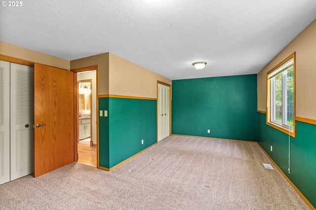 unfurnished bedroom with visible vents, carpet floors, a textured ceiling, and a closet