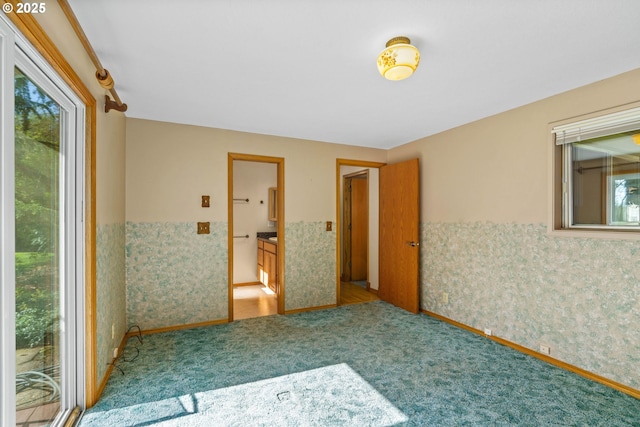 empty room featuring wainscoting, carpet flooring, and plenty of natural light