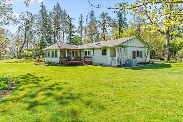 rear view of property with board and batten siding, a yard, crawl space, and a wooden deck