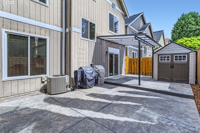 view of patio / terrace featuring fence, central AC, a storage shed, an outbuilding, and a grill