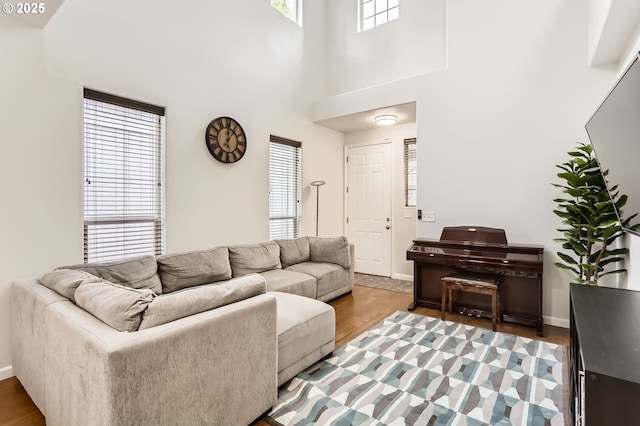 living area featuring baseboards, light wood finished floors, and a towering ceiling