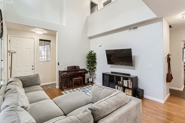 living area with baseboards, light wood-type flooring, and visible vents