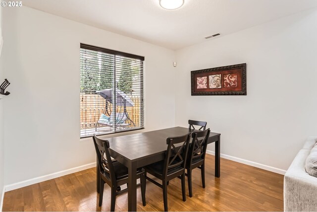 dining area featuring visible vents, baseboards, and wood finished floors
