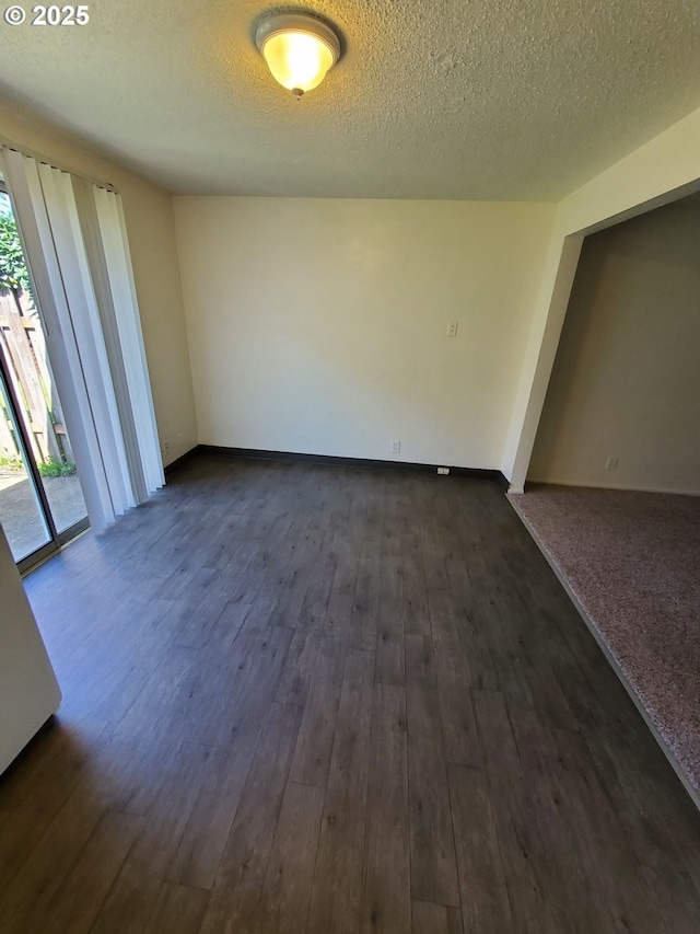 spare room featuring dark wood-type flooring, plenty of natural light, and a textured ceiling