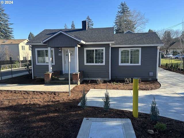 view of front of home featuring a shingled roof, a chimney, and fence