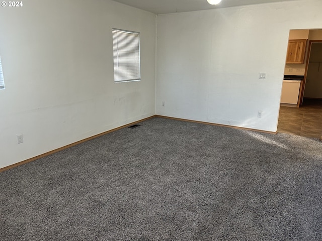 unfurnished room featuring baseboards, visible vents, and dark carpet