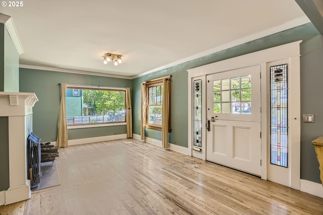 foyer entrance with ornamental molding, wood finished floors, baseboards, and a fireplace