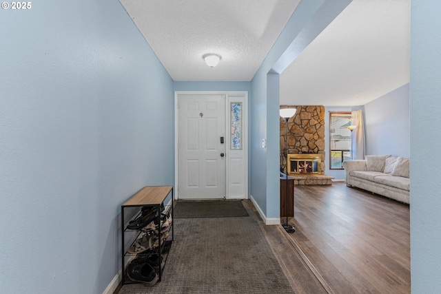 entrance foyer featuring dark hardwood / wood-style flooring, a fireplace, and a textured ceiling