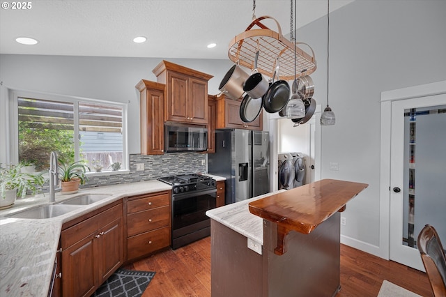 185 Lynx Ave, Aumsville, OR 97325 - kitchen featuring separate washer and dryer, stainless steel appliances, backsplash, brown cabinetry, and dark wood finished floors