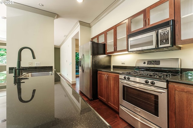 1951 NW Hoyt St, Portland, OR 97209 - kitchen featuring appliances with stainless steel finishes, a sink, ornamental molding, dark stone counters, and glass insert cabinets