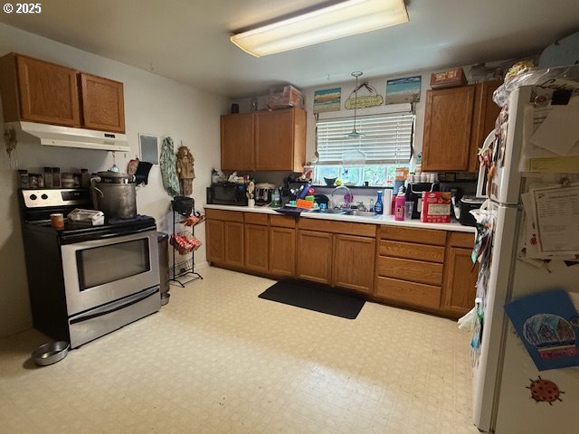 629 NE Johnson St, Myrtle Creek, OR 97457 - kitchen with stainless steel electric stove, under cabinet range hood, brown cabinetry, light countertops, and freestanding refrigerator