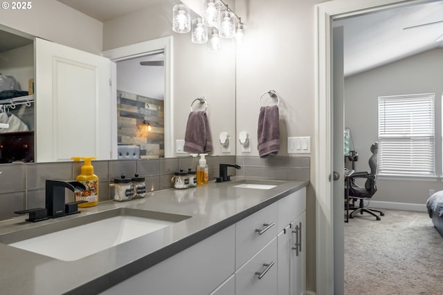 full bathroom with double vanity, a sink, baseboards, and lofted ceiling