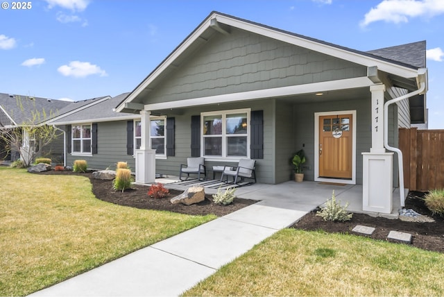 view of front of property with a porch, fence, and a front yard