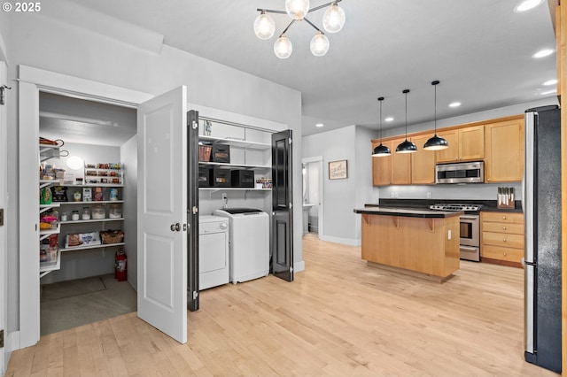 2733 NE 77th Pl, Portland, OR 97213 - kitchen featuring stainless steel appliances, washer and dryer, dark countertops, light wood-type flooring, and a breakfast bar area