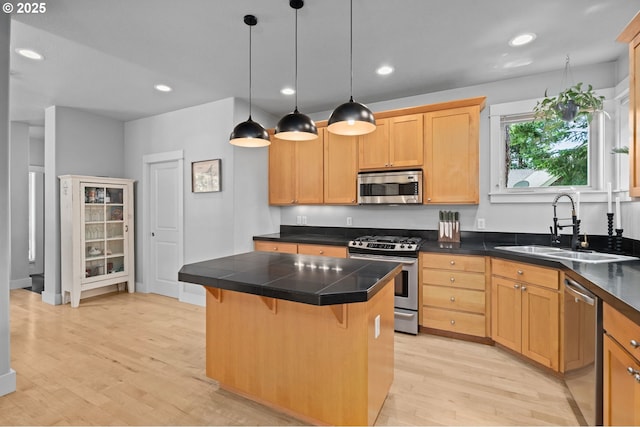2733 NE 77th Pl, Portland, OR 97213 - kitchen featuring appliances with stainless steel finishes, light wood finished floors, a kitchen bar, a center island, and pendant lighting