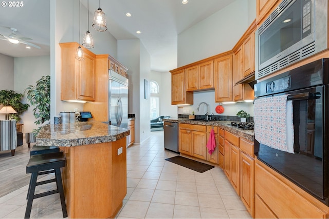 kitchen with a kitchen bar, sink, hanging light fixtures, light tile patterned floors, and black appliances