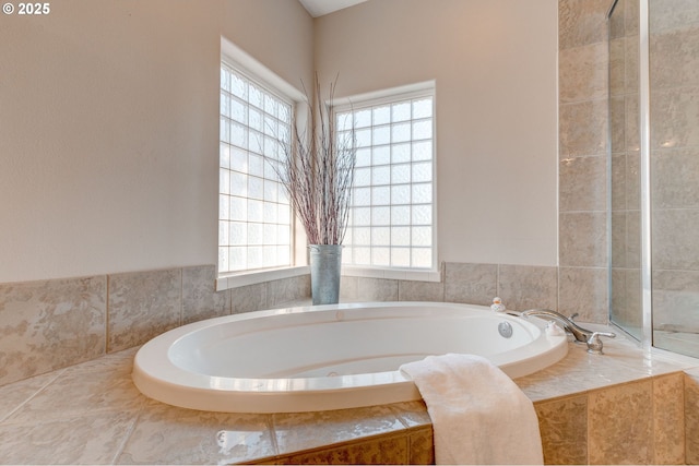 bathroom featuring tiled tub and a wealth of natural light