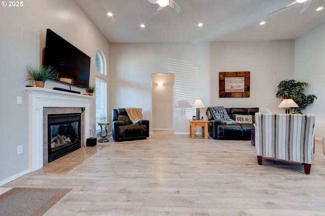 living room with light wood-type flooring, a fireplace, and ceiling fan