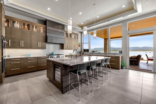 794 S A St, Washougal, WA 98671 - kitchen featuring custom range hood, a breakfast bar, a raised ceiling, a center island with sink, and recessed lighting