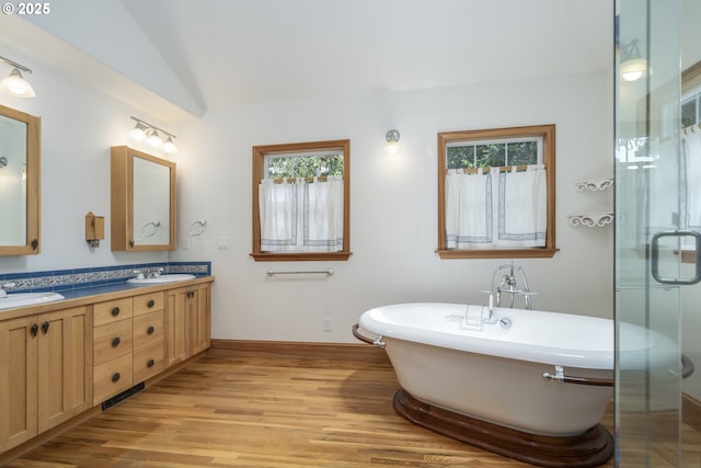 110 SW 61st St, South Beach, OR 97366 - full bathroom featuring healthy amount of natural light, double vanity, wood finished floors, a freestanding tub, and vaulted ceiling
