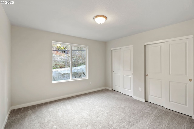 unfurnished bedroom featuring carpet and two closets