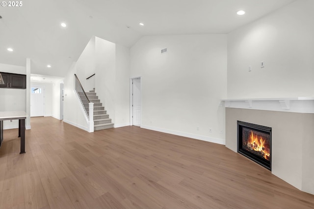 5591 N 93rd Ave Unit Lt206, Camas, WA 98607 - unfurnished living room with recessed lighting, stairway, light wood-style flooring, high vaulted ceiling, and a glass covered fireplace