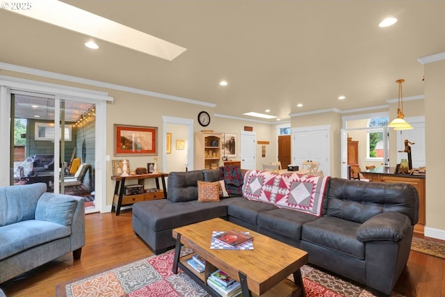 living area with recessed lighting, wood finished floors, a skylight, and ornamental molding