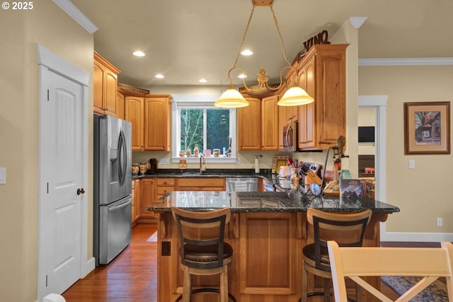 kitchen with dark wood-type flooring, a kitchen bar, ornamental molding, recessed lighting, and appliances with stainless steel finishes