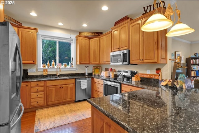 kitchen with crown molding, stainless steel appliances, light wood-type flooring, and a sink